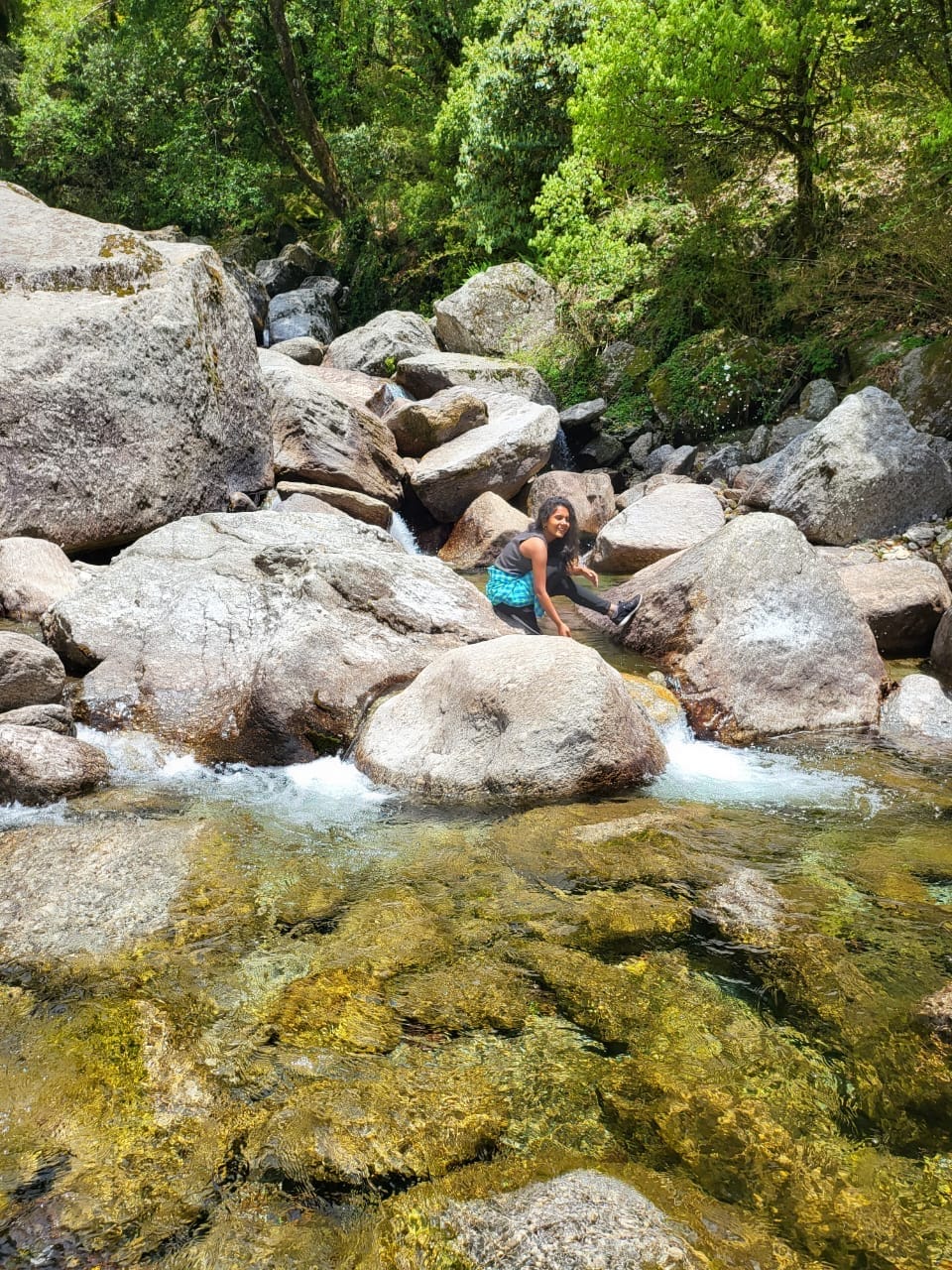 A guest sitting by a clear mountain stream between large boulders