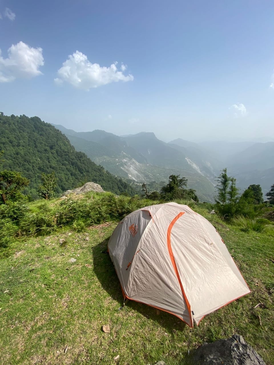A tent pitched on a grassy ridge with views over a valley