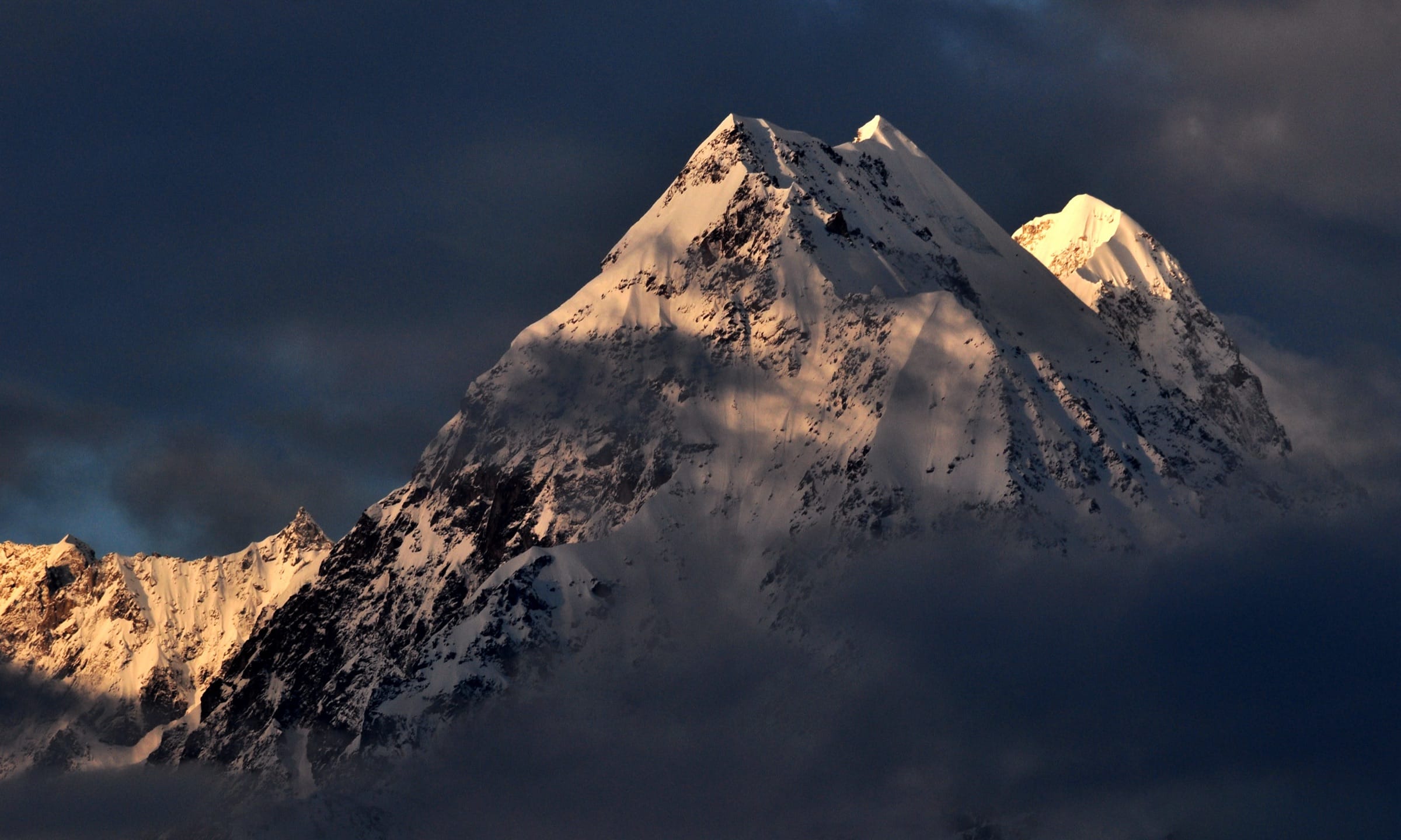 The Panchachuli peaks catching sunlight below dark clouds