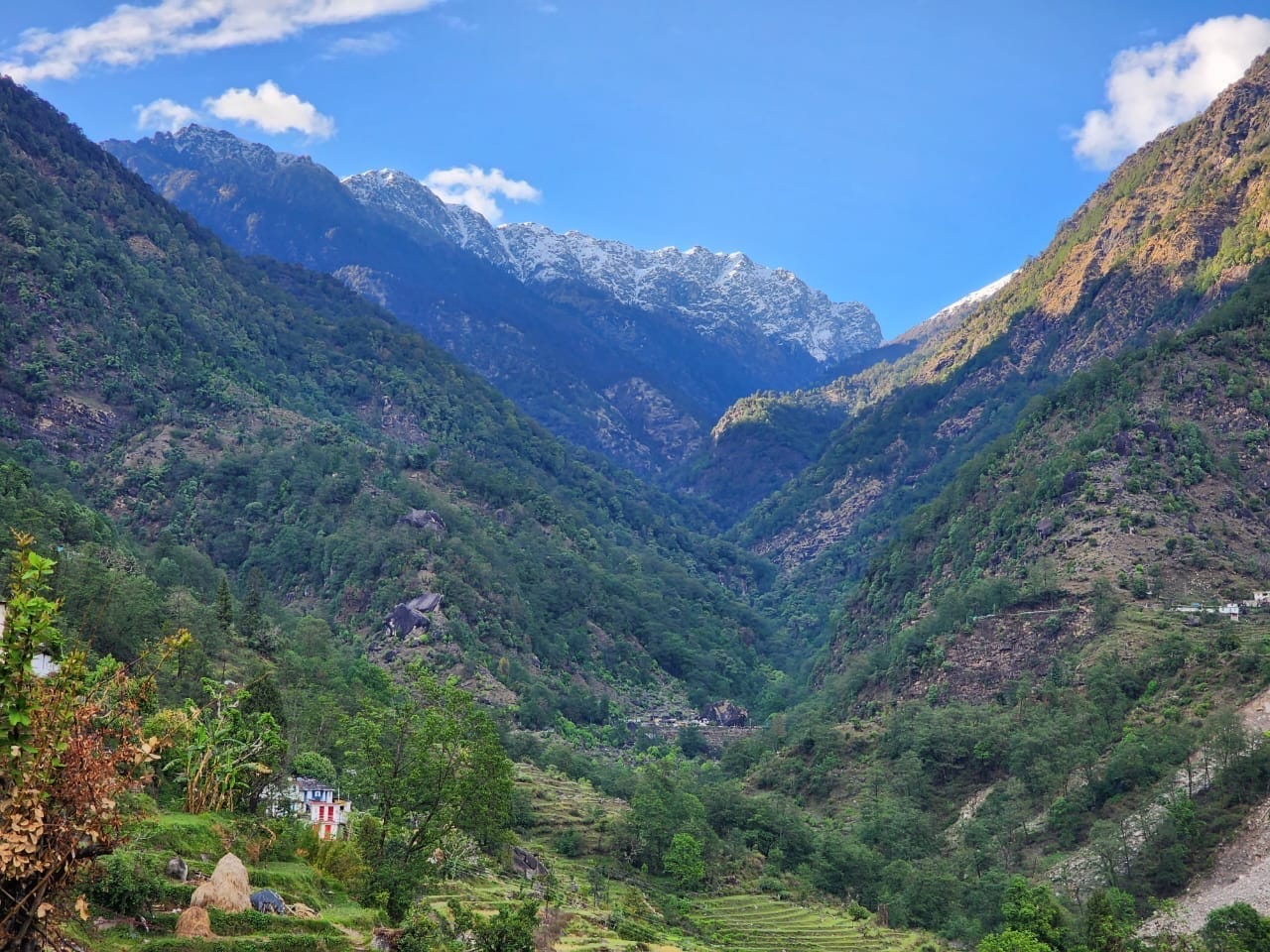 A Himalayan valley with terraced fields, village homes and a snowy ridge
